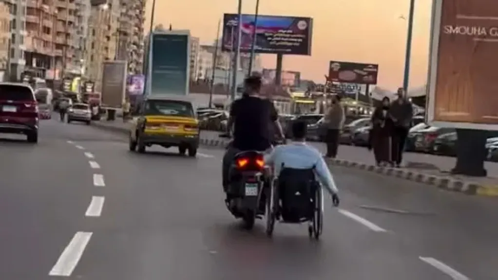شاب يساعد صديقه على كرسي متحرك ويخطف قلوب المصريين